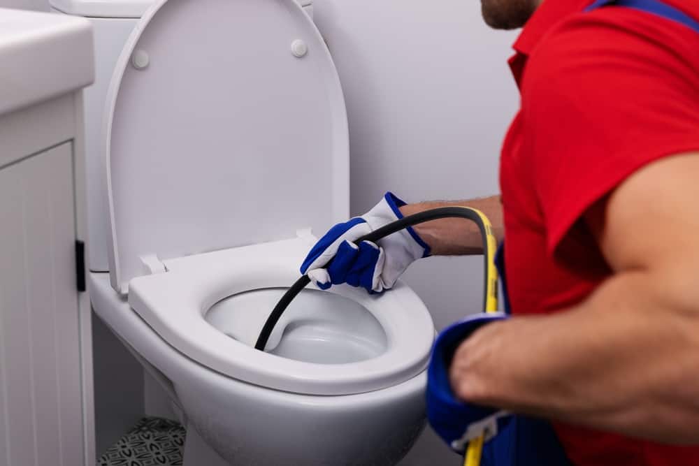 plumber unclogging toilet